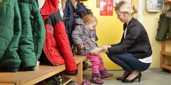 Mutter mit Kind beim Umziehen in der Kita Mutter mit Kind beim Umziehen in der Kita